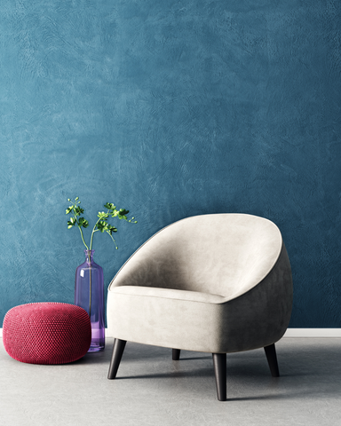 Room with blue wall, white chair and magenta puff pillow