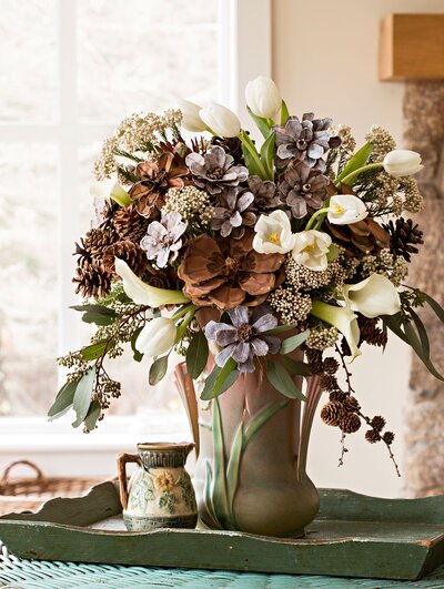 brown green and white winter flower arrangement on table 