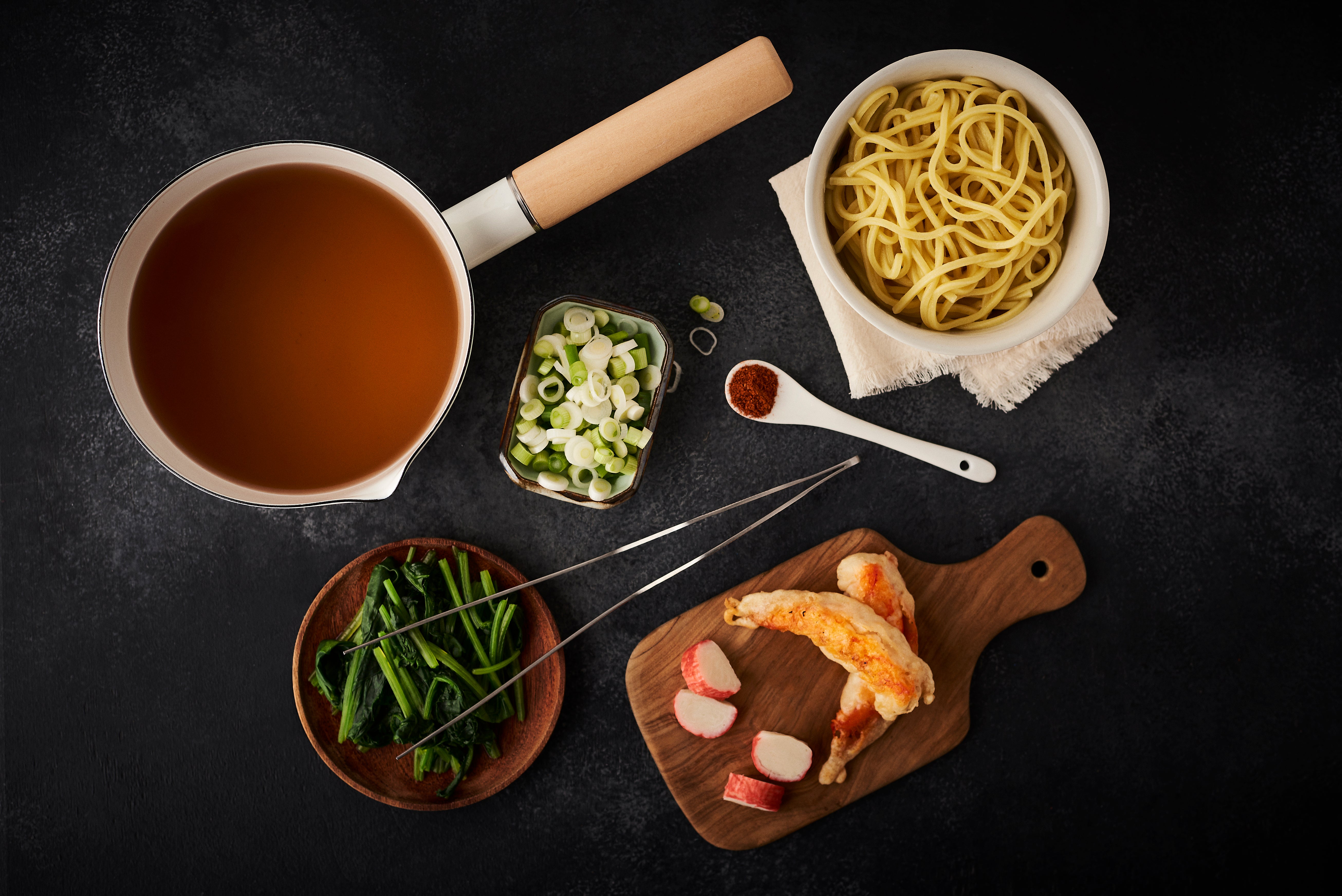 prepared ingredients to make soba noodle soup laid out in bowls and on chopping board