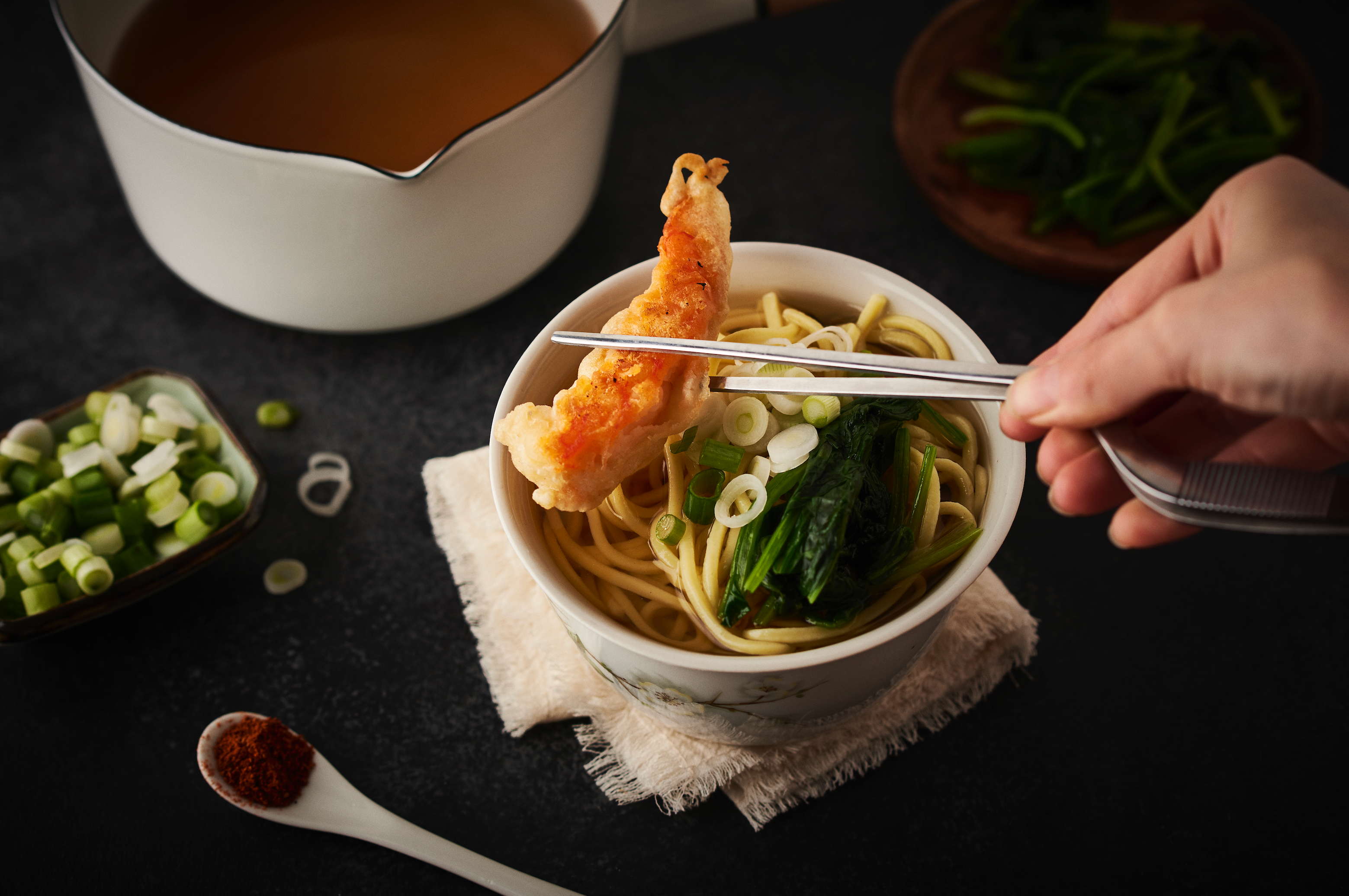 Chopsticks reaching into bowl picking up noodles from the completed soba noodle soup