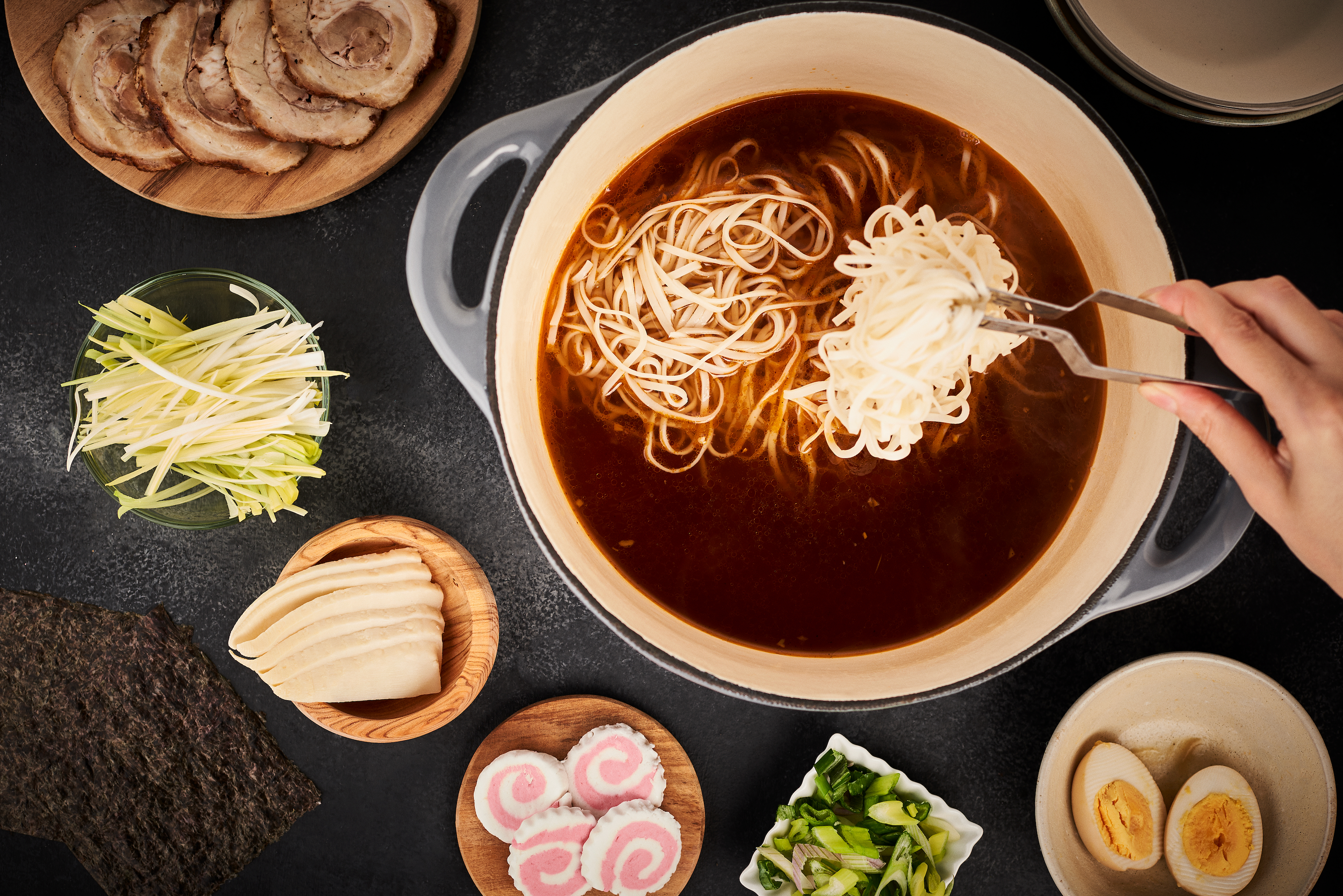 Ingredients in little bowls surrounding the home made soup with noodles