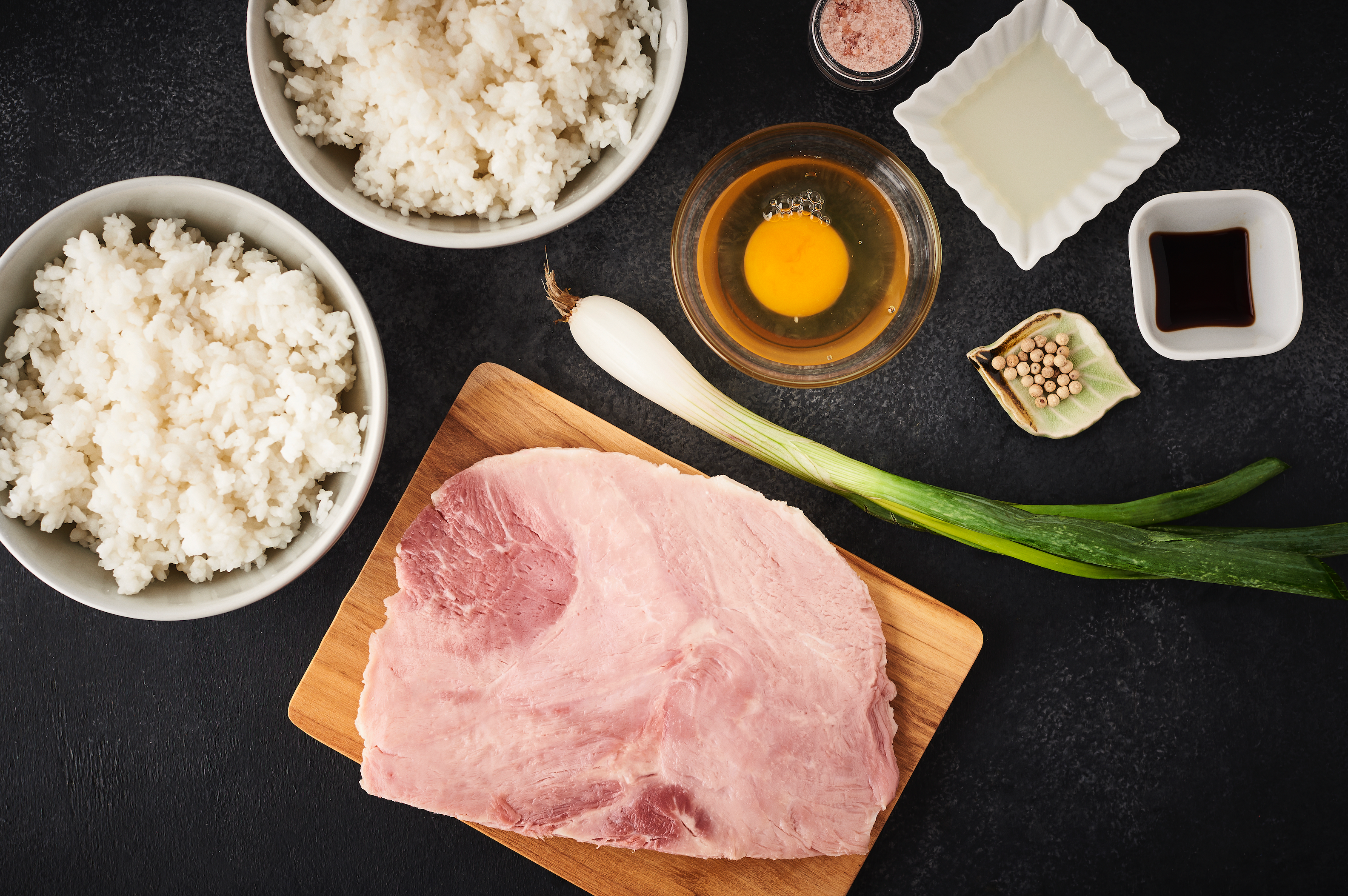 Ingredients for Japanese egg fried rice laid out in small jars on table, picture shot from above