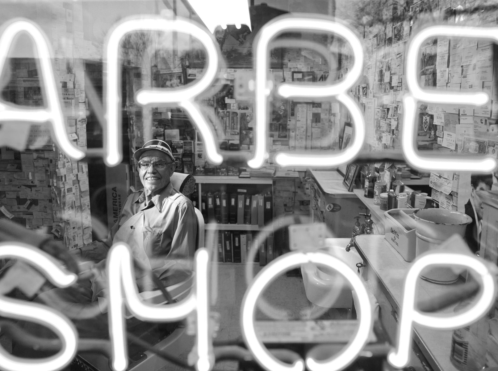 Man in barber chair through neon sign