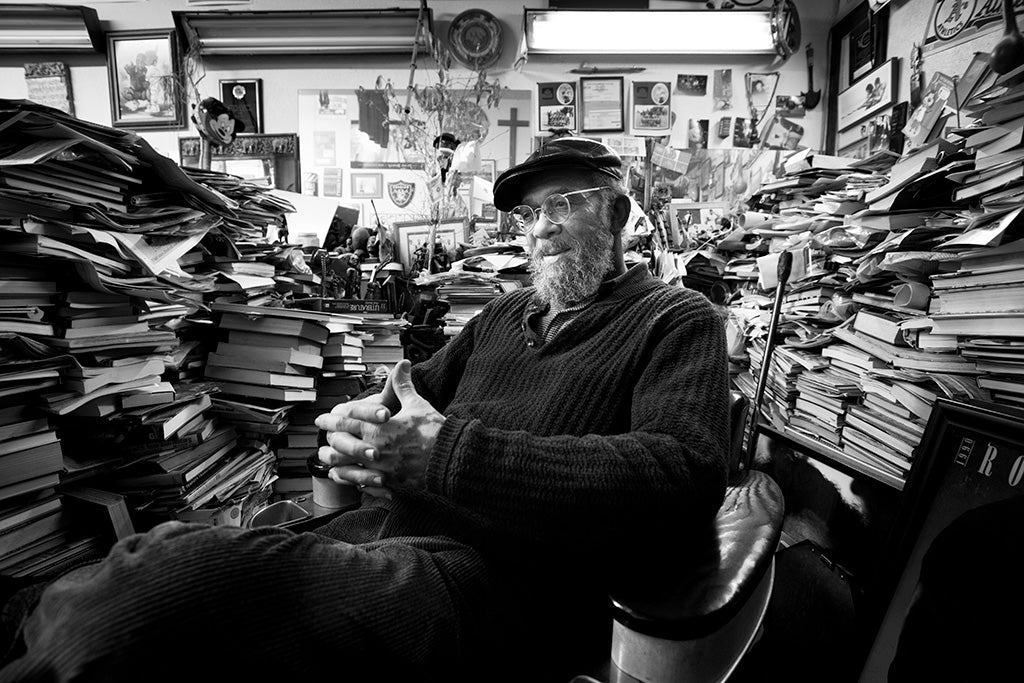Man sitting in barber chair surrounded by books