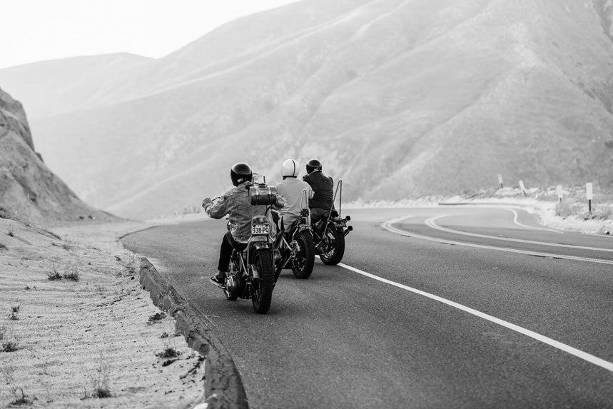 Three men riding motorbikes in the mountains
