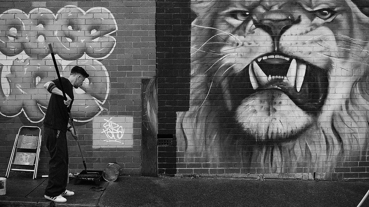 Man sweeping in front of grafitti wall