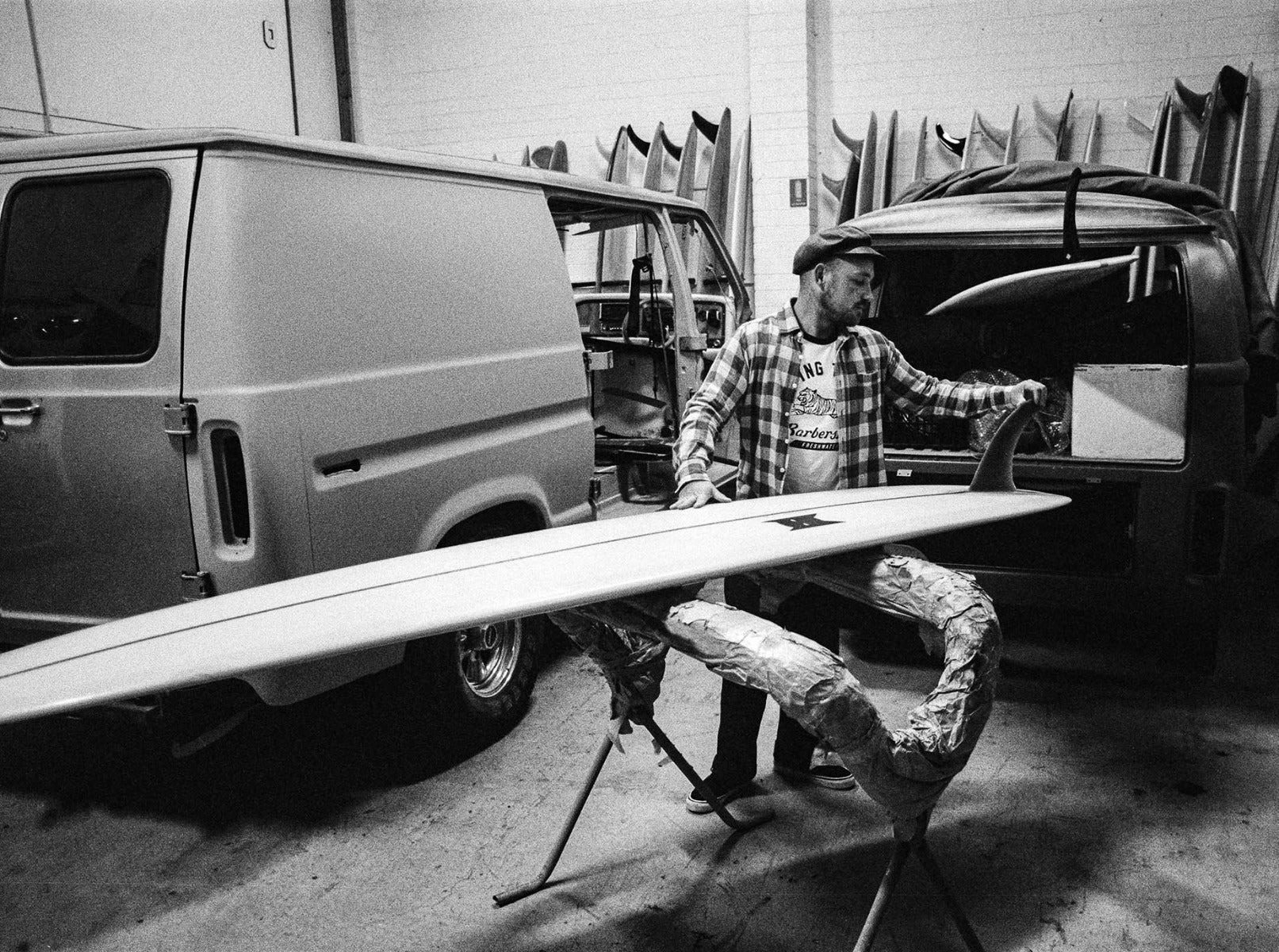 Man waxing surfboard in front of Van