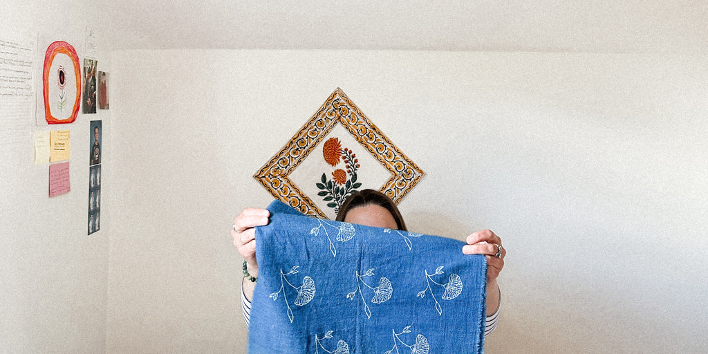 A photo of Laura Chenoweth holding up a piece of blue with block printed white flowers on cotton fabric from India
