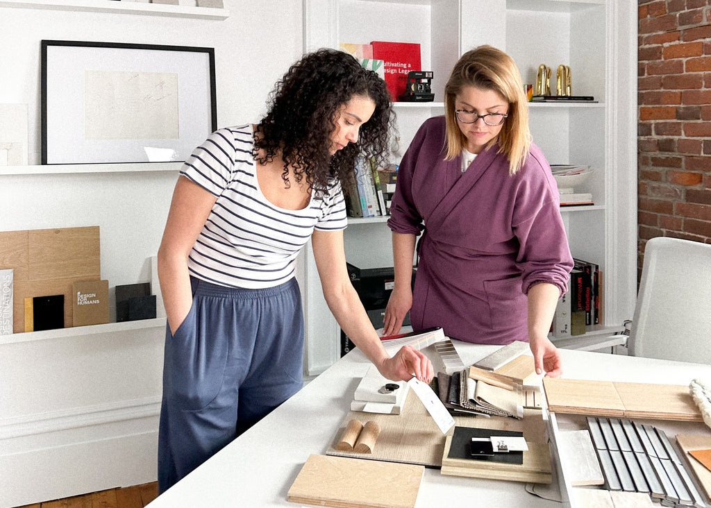 Mimi and Krysia working together on a table going through different elements of design in their studio in Halifax, Nova Scotia 