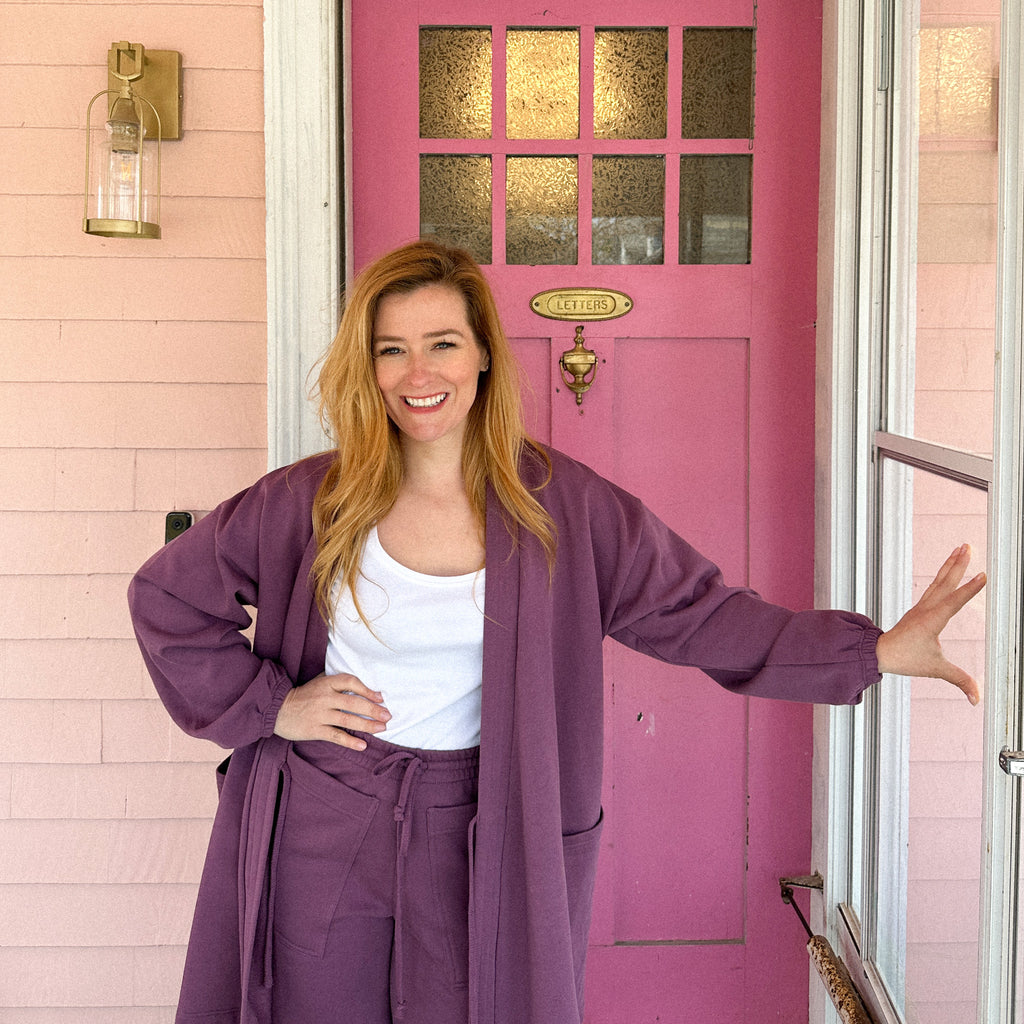 Rebekah standing in front of her pink home's dark pink front door