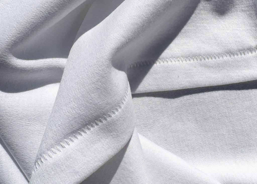 A close up image of white organic Pima cotton that features a tooth stitch hem 