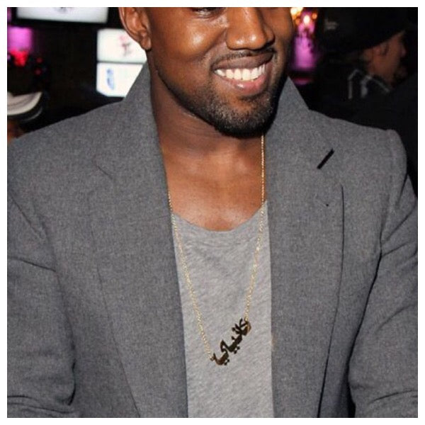 Kanye West portant un collier personnalisé avec son nom arabe en or.