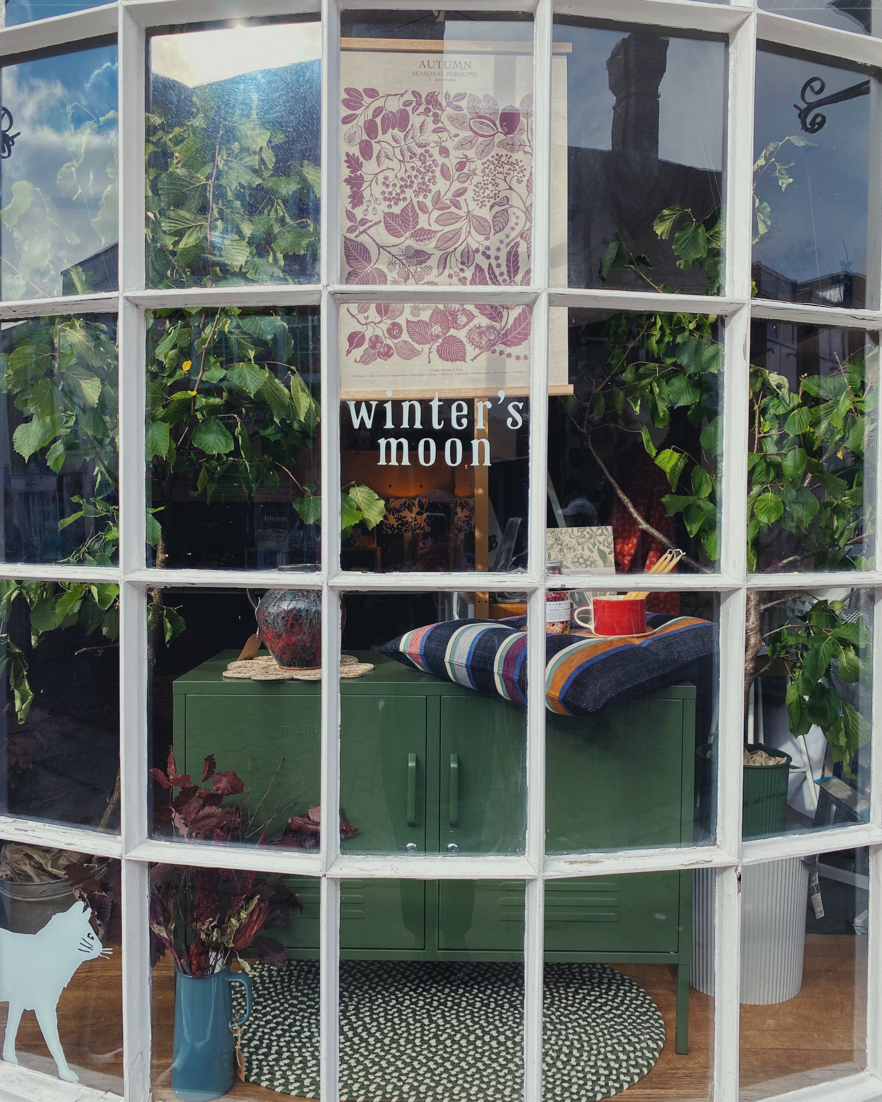 Winter's Moon Shop Autumn Window, with olive green locker and autumn seasonal foraging poster