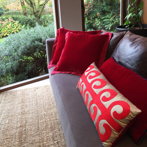 Gri kanepede kirmizi kadife ve bej ustune kirmizi hayat agaci desenli yastiklar_Red velvet cushions and beige silk pillow with red tree of life motif on a sofa facing the garden