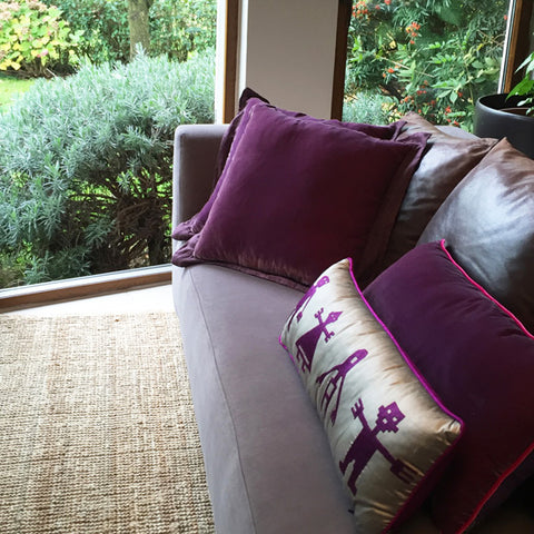 Bahceye bakan gri kanepede mor kadife ve gri ustune mor insan desenli ipek yastiklar_Purple velvet cushions and silver grey silk pillow with purple human motifs on a sofa facing the garden