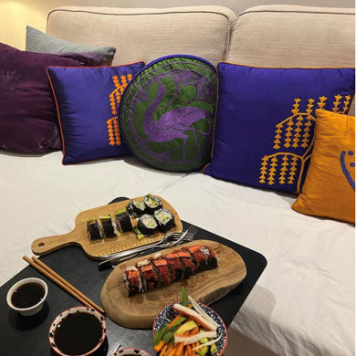 Bej kanepede islemeli kirlentler ve sehpada susi_Embroidered cushions on the sofa behind the coffee table with sushi on it