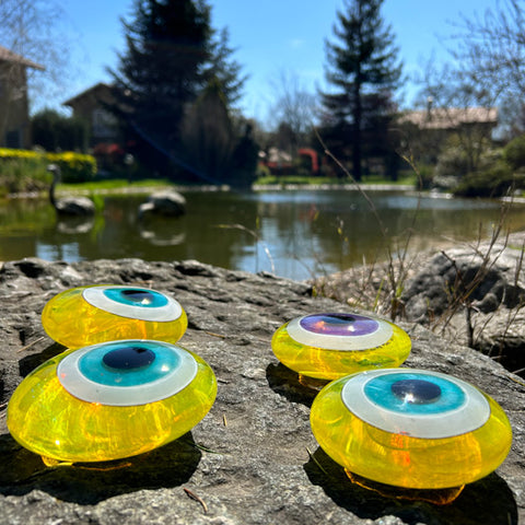 Golet yaninda parlak sari cam goz boncuklari_Bright yellow evil eye beads beside the pond