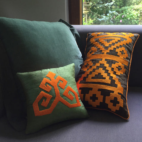 Pencerenin onundeki gri kanepede turuncu nakisli cagla yesili ve fume ipek ve ipek kadife kirlentler_Sage green and dark grey silk and silk velvet cushions on the gray sofa by the window