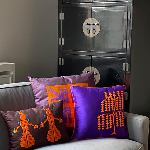 Siyah dolabin onundeki kanepenin kosesinde motifli turuncu ve mor ipek yastiklar_Orange-and purple silk cushions with motifs at the corner of sofa in front of the black cabinet