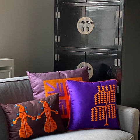 Siyah dolabin onundeki kanepenin kosesinde motifli turuncu ve mor ipek yastiklar_Orange and purple silk cushions with motifs at the corner of sofa in front of the black cabinet