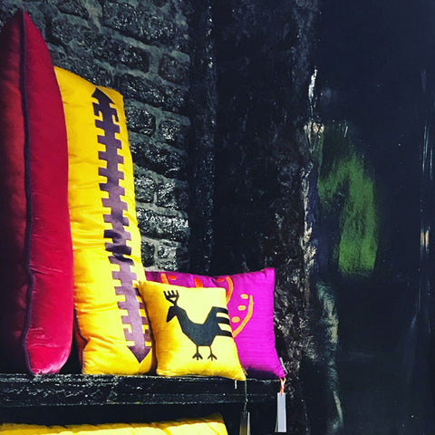 Siyah duvarin rafinda sari ve pembe kirlentler_Pink and yellow cushions on the shelf of a black wall