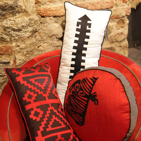 Tas duvarin onundeki kirmizi koltukta islemeli kirmizi siyah beyaz kirlentler_Embroidered red black and white cushions on the red armcahir in front of the stone wall