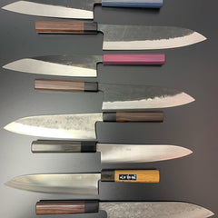 Eine Auswahl an Griffmaterialien für Damaszenermesser, darunter Olivenholz, Büffelhorn, Pakkaholz und Walnussholz