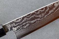 Eine Nahaufnahme eines Damastmessers, das sein kompliziertes und einzigartiges Muster zeigt, hergestellt in Japan.