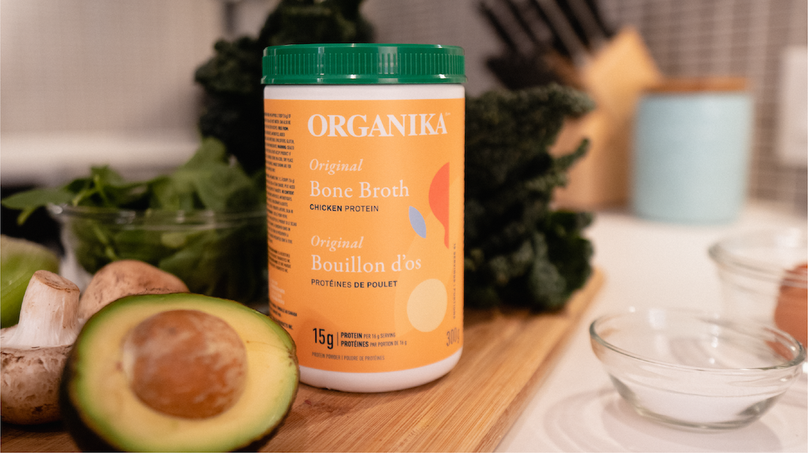 Organika Chicken Bone Broth Powder on a counter with an avocado, mushrooms and green