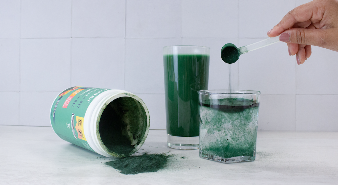 Organika's Spirulina powder being poured into a glass of water