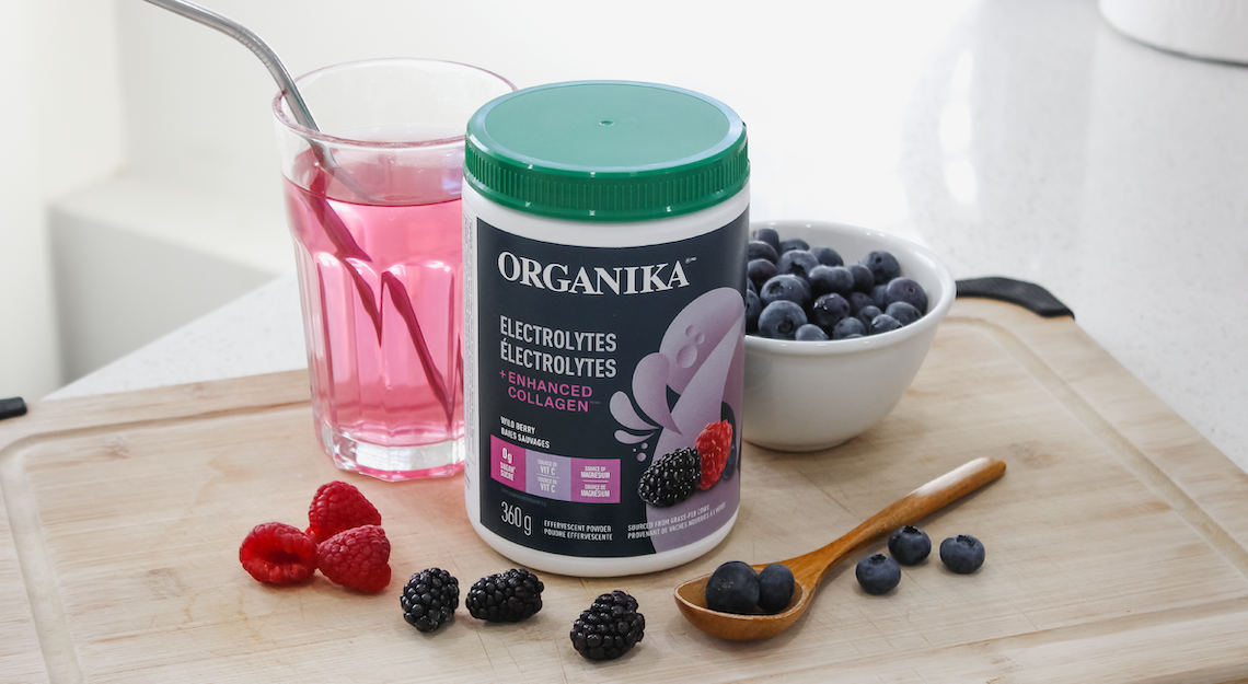 Organika's Electrolytes + Enhanced Collagen on a counter with a bowl of berries