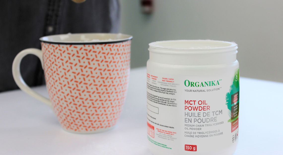 Organika's MCT Oil Powder on a table beside a mug