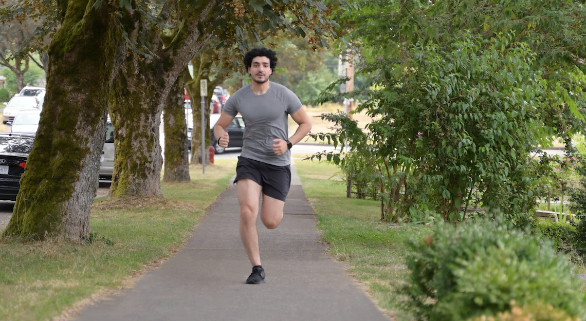 Man going for a jog on a path with greenery around 