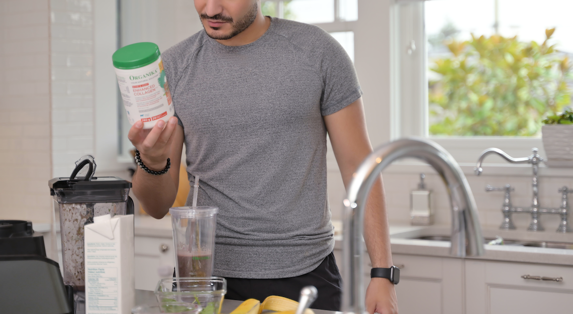 A man in the kitchen making a smoothie with Organika's Enhanced Collagen Bone and Joint