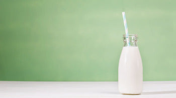 A glass of milk on a table with a straw