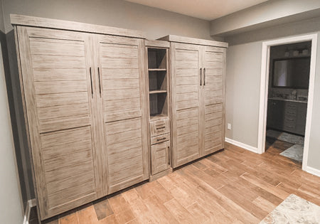 Two weathered grey full murphy beds with a cabinet in between