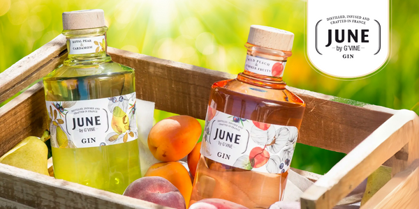 2 bottles of June by G'Vine gin bottles in a summer wooden fruit case with peaches, apricoats and pears