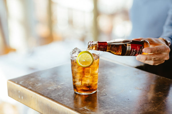 Fever-Tree Cola poured in an iced glass for a Rum & Cola with lemon wedge as garnish