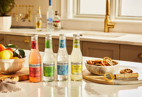 Fever-Tree mixed bottles lined up in a kitchen counter with fruit and spices around