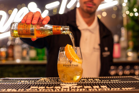 Bartender pouring Fever-Tree Ginger Ale on a iced glass in a night club in Bangkok, Thailand