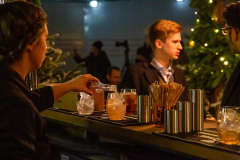 bartender pouring Fever-Tree soda on a glass in a club with a customer looking around