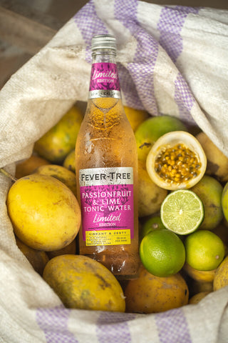 Fever-Tree soda bottle on top of its ingredients passion fruit and lime at the production site