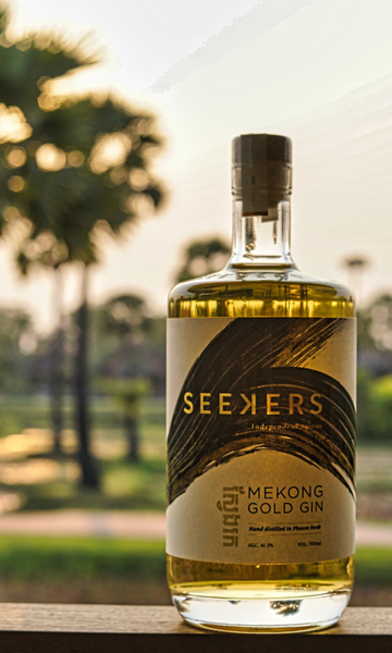 Seekers Gold Gin bottle with sunset light and tall trees in background