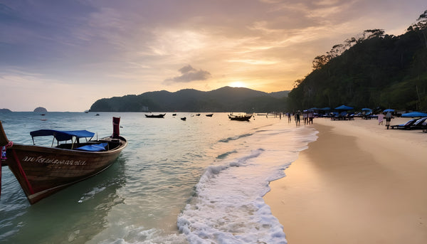 sunset on the beach in phuket with a long tail boat on the shore