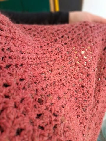 A close up shot of lace crochet in a red colourway. It's a simple repeat and the yarn is slightly flecky and heathered. 