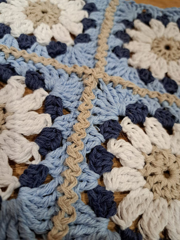 Four, floral granny sqaures in shades of beige, blue and cream crocheted together with beige.