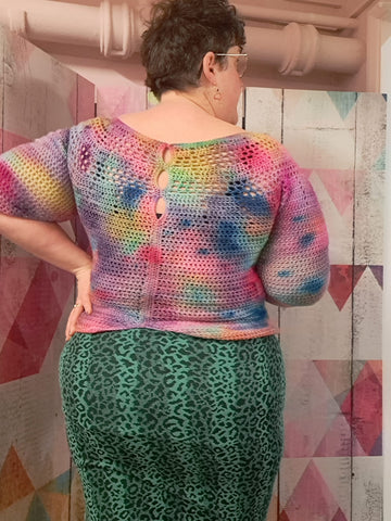 The back of a fat, white, woman with short brown hair. She's wearing a green leopard-ish print tight skirt and a tie dye effect, crochet jumper with keyhole detail by the neck.