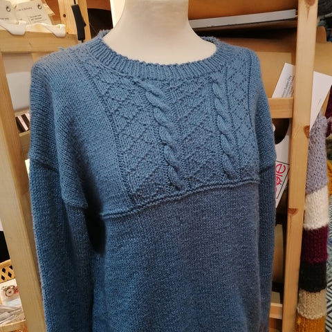 Pattern 5484, a navy blue gansey with a cable panel across the chest.