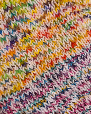 A swatch of knitting with the stitches laid diagonally. Each stitch is a different colour and it looks very crazy.