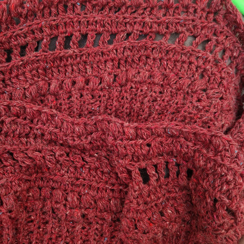 A swatch of very textured crochet fabric in a wine red.